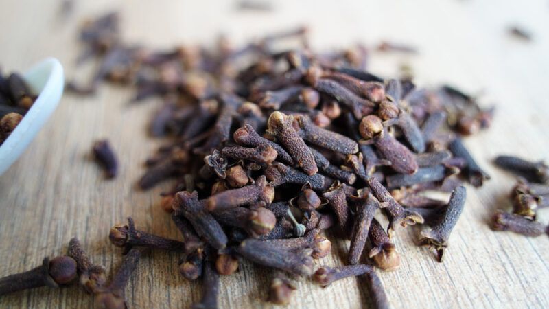 a closeup image of a mound of cloves on a wooden surface