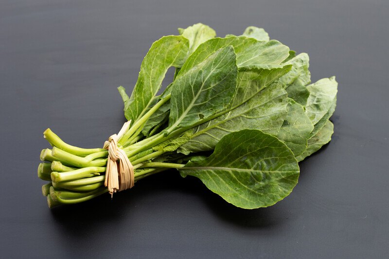 a bundle of Collard Greens on a black surface