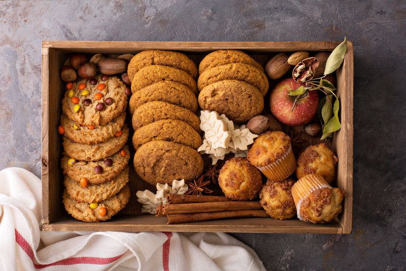 a wooden box in autumn style with a variety of cookies and cupcakes inside