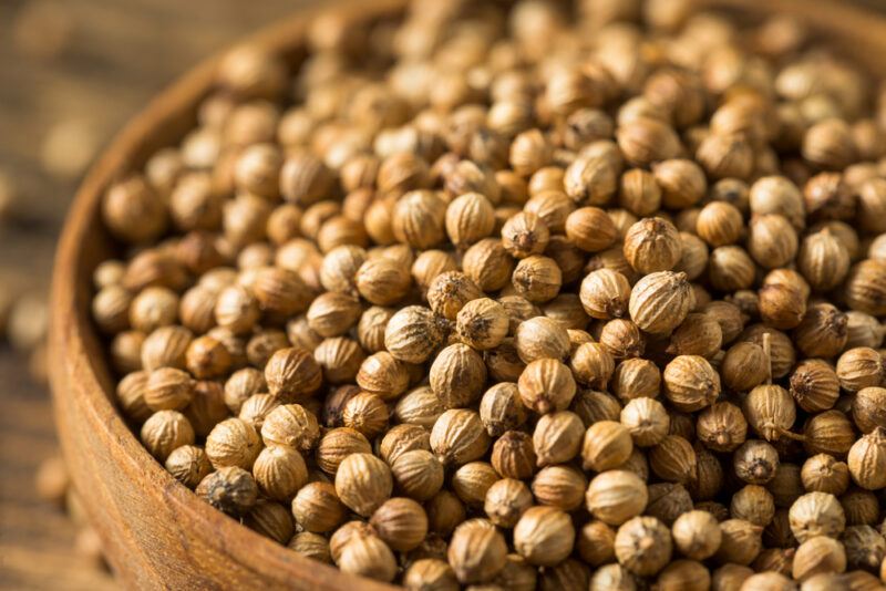 closeup image of coriander seeds in a wooden bowl