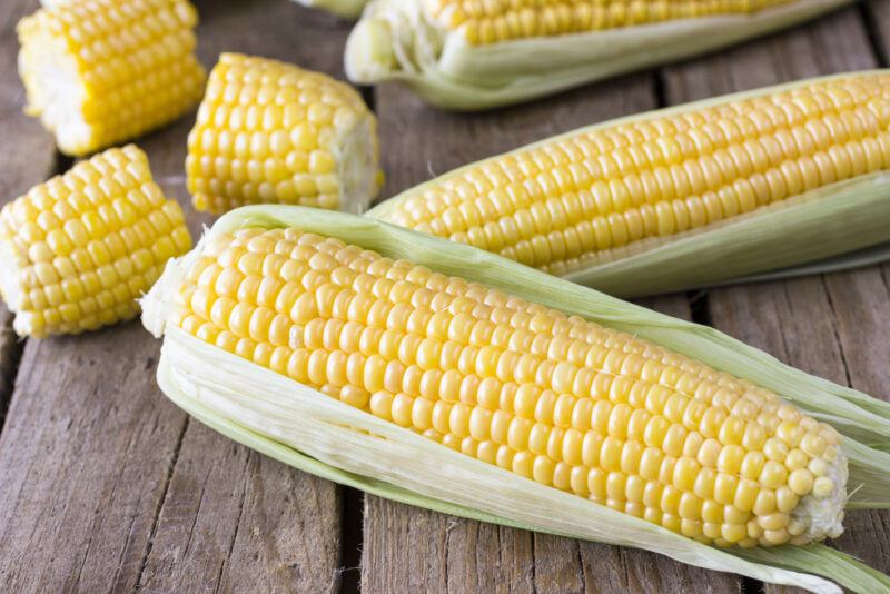 on a rustic looking wooden surface is a spread of corn on the cobs