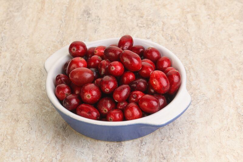 on a marbled surface is a white and blue bowl full of fresh cranberries