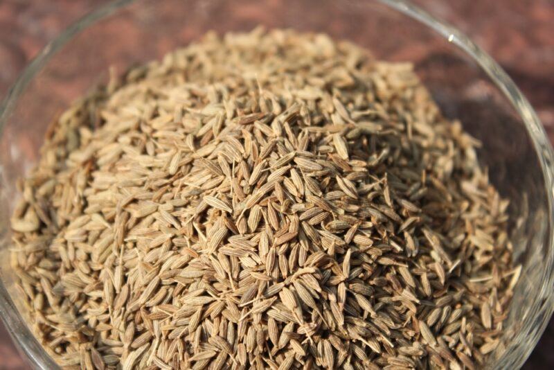 closeup image of a clear glass bowl of cumin seeds