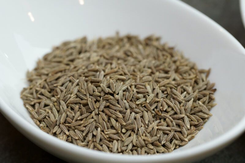 a closeup image of a white bowl with cumin seeds