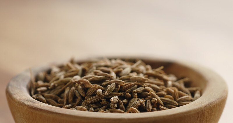 macro shot of cumin seeds in a wooden bowl