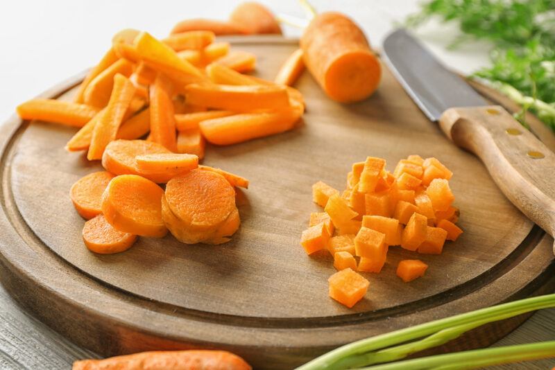 carrots on a chopping board, some thinly sliced, some cut into strips, and some diced