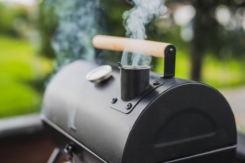 depth of field charcoal smoker with smoke billowing from top