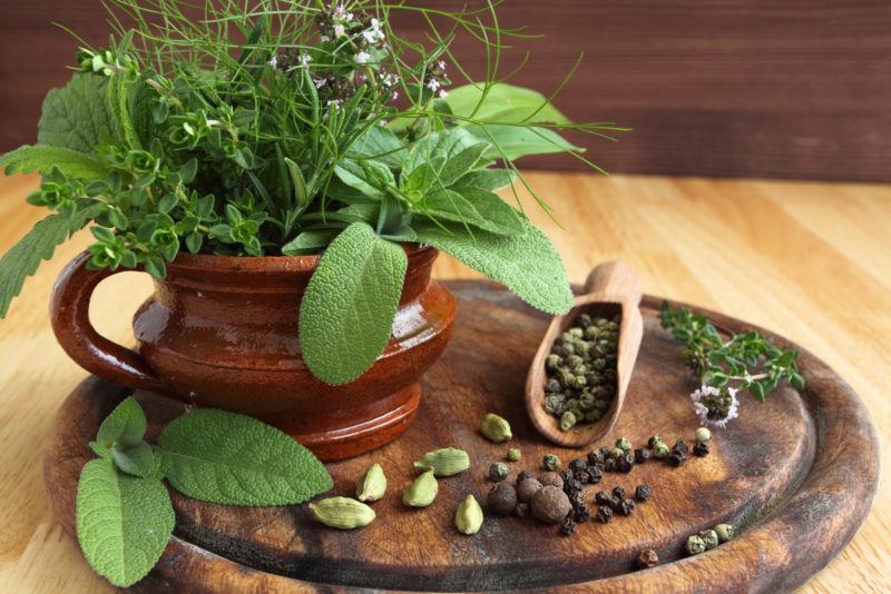 pepper, pergano, other herbs on a ceramic pot, placed on top of a circular wooden serving tray