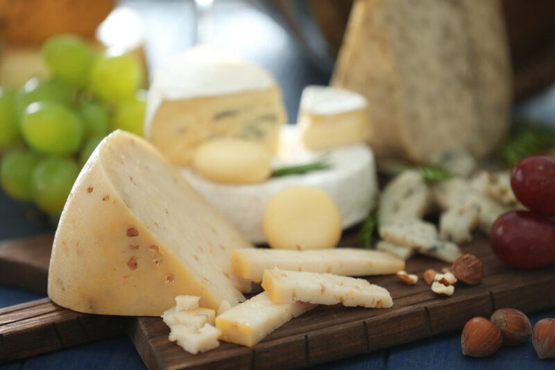 on a dark wooden board is a spread of different types of cheese