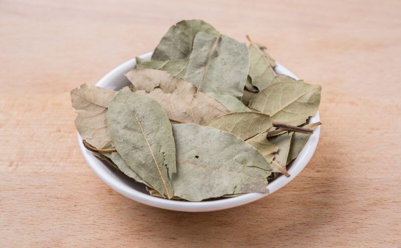 on a wooden surface is a white bowl full of dried bay leaves