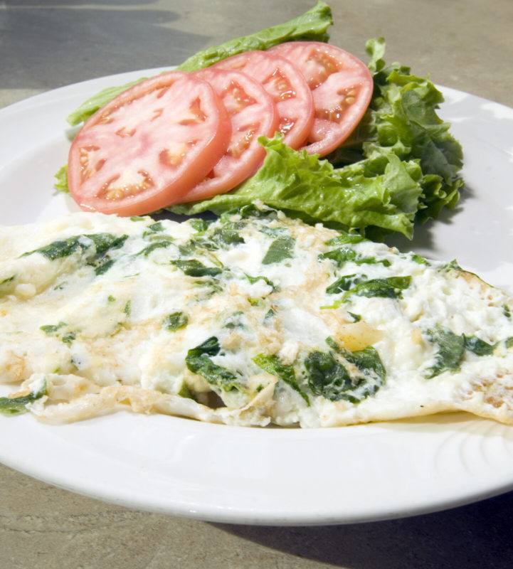 egg white omelet cooked with herbs, served with slices of tomato and lettuce on a white plate