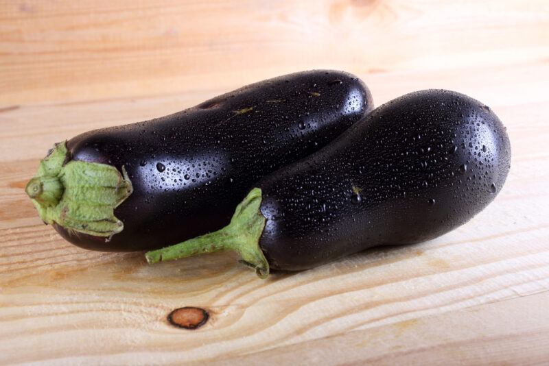 on a wooden surface is a couple fresh eggplants