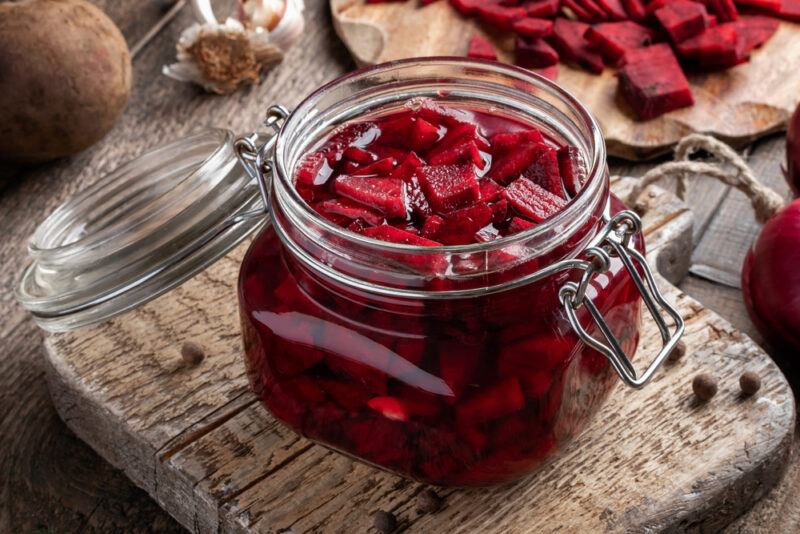 a jar of fermented beets on a rustic looking wooden chopping board with loose spices around it