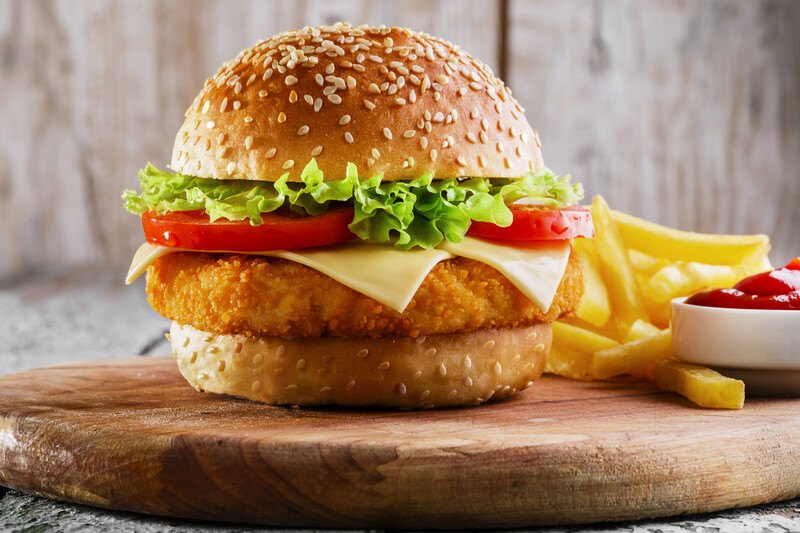 a fish sandwich on a serving board with fries and ketchup to represent wendy's fish sandwich 