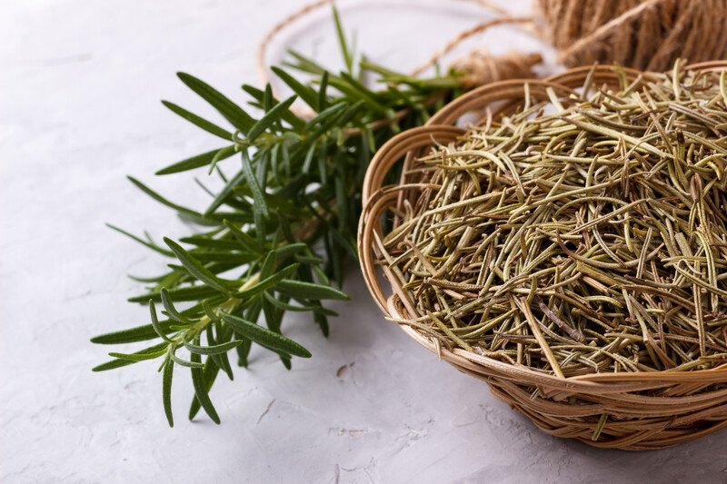 on a marble surface is a basket full of dried thyme with a bunch of fresh thyme beside it