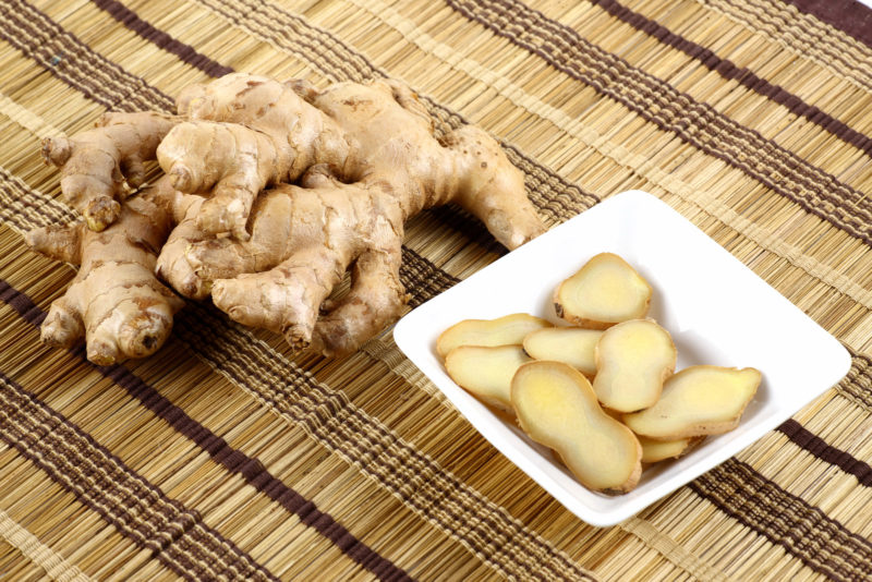 fresh and sliced ginger placed on top of a woven placemat