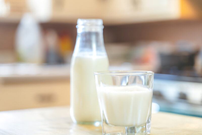 on a wooden table is glass and bottle of fresh milk