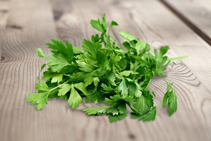 on a wooden surface is a closeup image of a bunch of fresh parsley