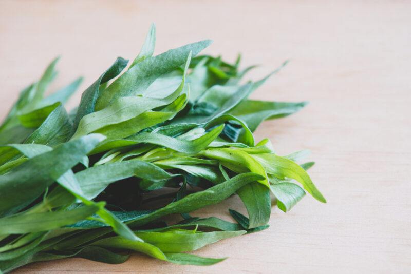 on a wooden surface is a partial image of a bunch of fresh tarragon