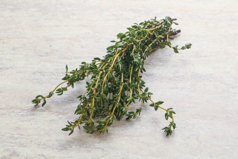 on a marbled surface is a bunch of fresh thyme