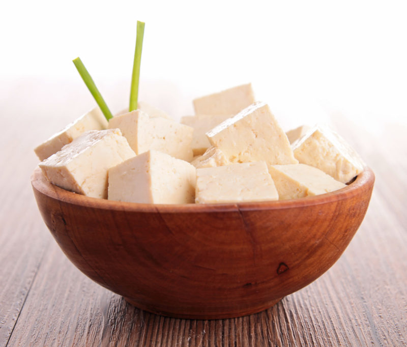 a wooden bowl filled with fresh blocks of tofu