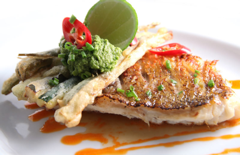 fried red snapper served with crispy skin, guacamole, and lime wedge