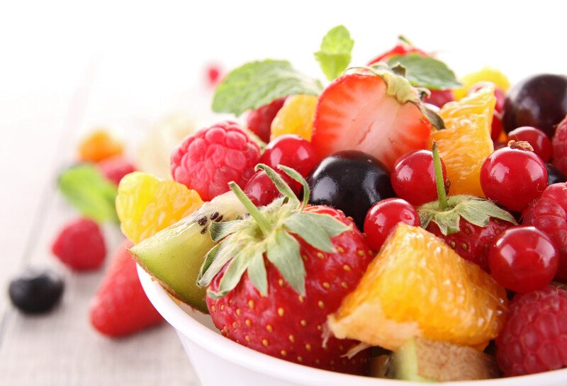 closeup image of a bowl full of different vegetables with loose berries beside it