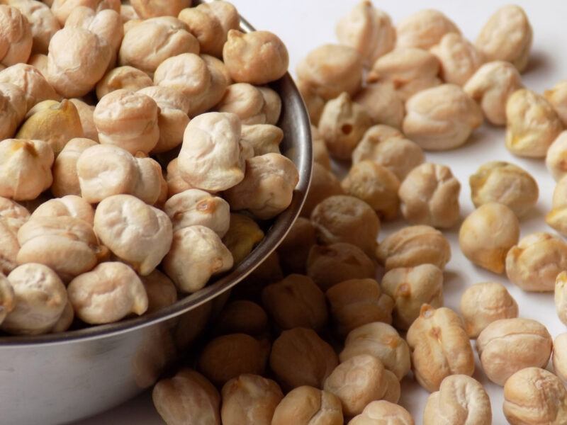 closeup image of a metal bowl full of garbanzo beans with loose beans beside it