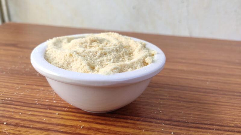 on a wooden table is a white bowl full of garlic powder