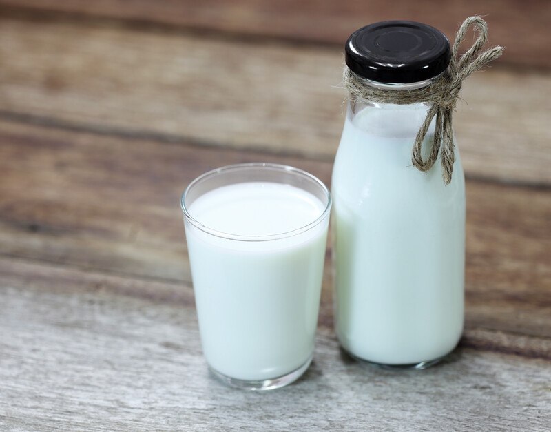 on a wooden surface is a glass and bottle of milk