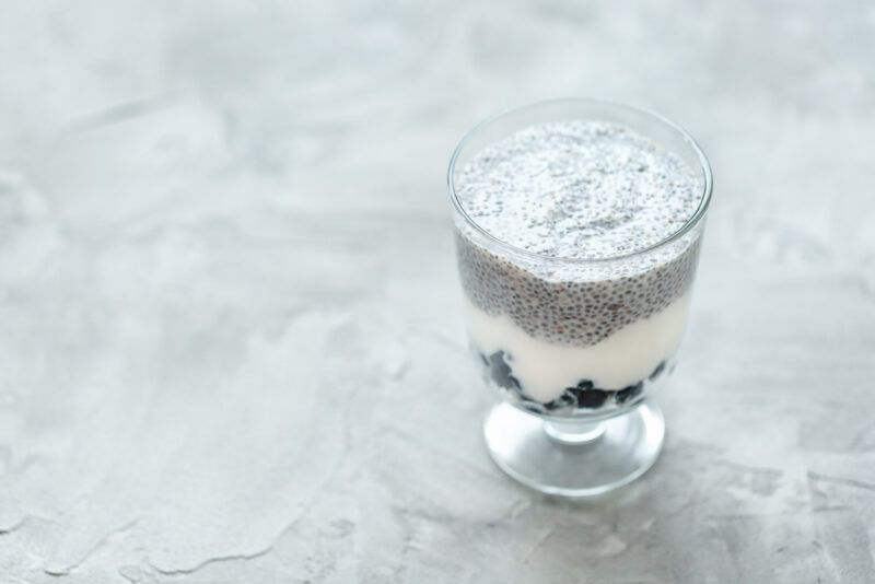 on a concrete surface is a stemmed glass of chia pudding