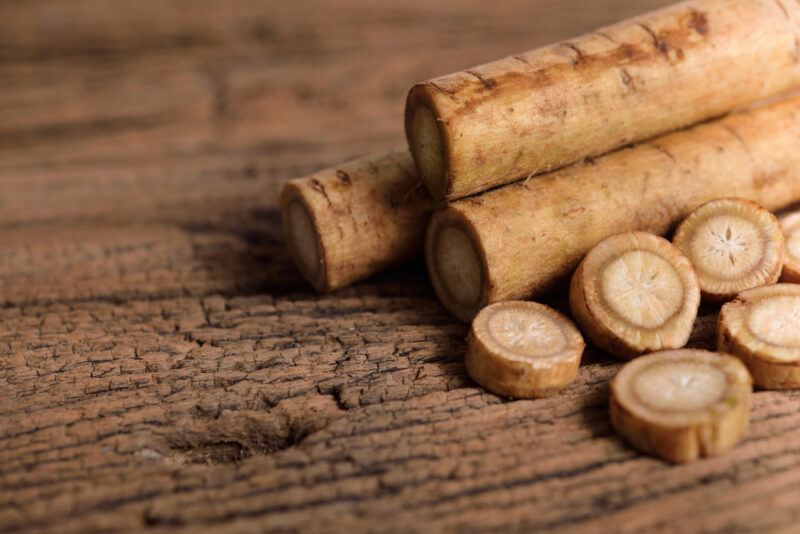 on a rustic looking wooden surface are gobo or burdock root, some are sliced thinly