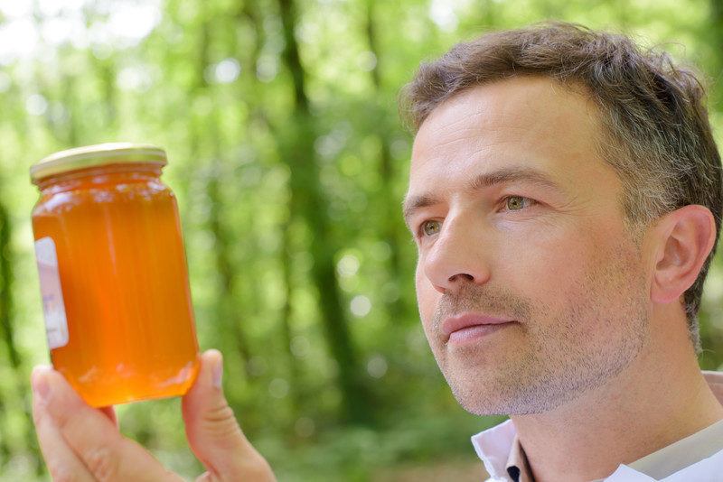 middle-aged man looking at gourmet honey, received in his gourmet food of the month club subscription box