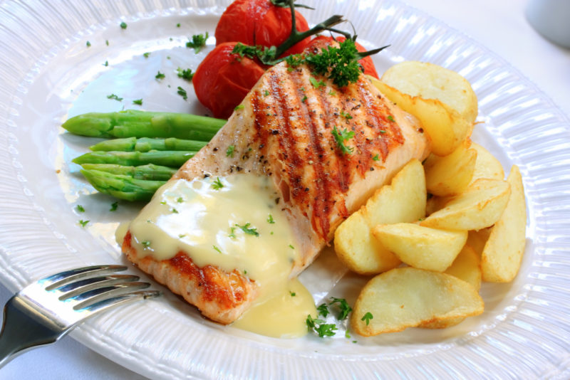 grilled fillet of salmon served with a Hollandaise sauce, cooked asparagus, cherry tomatoes and potato wedges