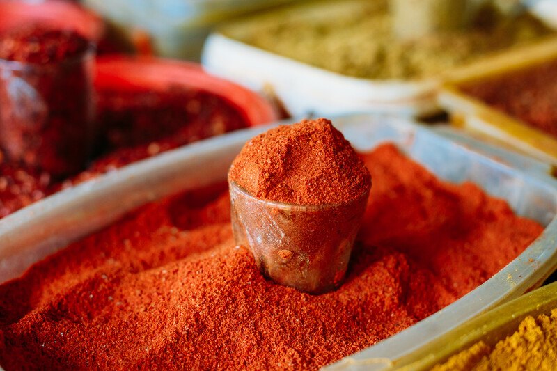 a rectangular plastic tub with ground cayenne, on top is a small glass full of ground cayenne as well