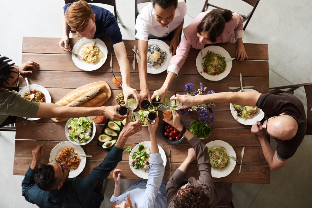 People toasting red wine on dinning table with Mexican food