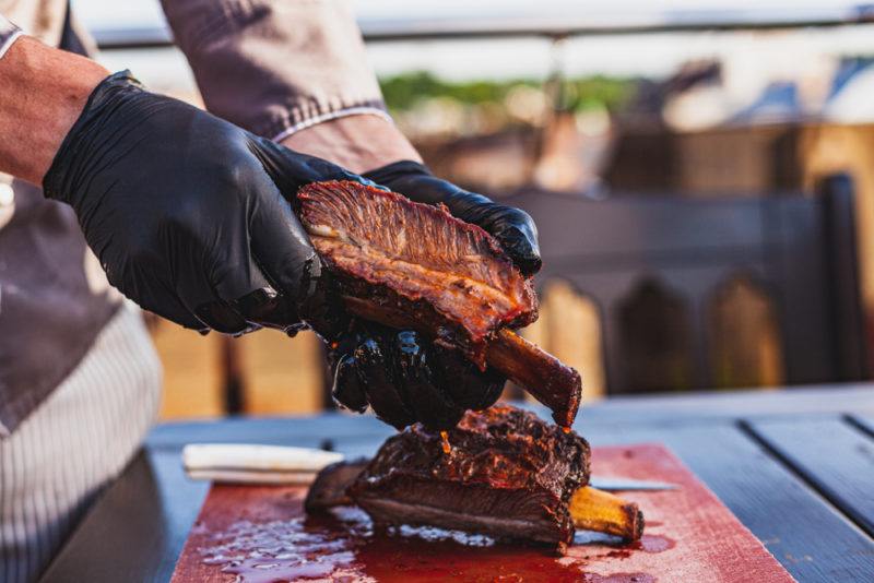 hand with black gloves holding smoked beef ribs