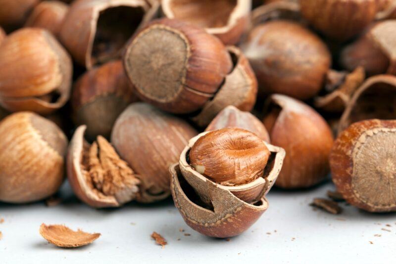 on a white surface is a closeup image of a pile of hazelnuts