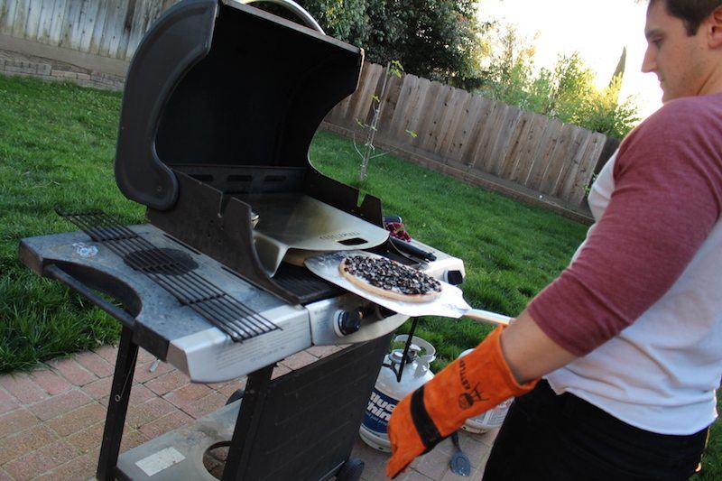 placing olive and cheese pizza into the gas grill at 650 degrees F