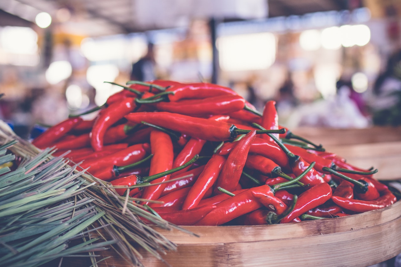 pile of red chili peppers on a bamboo platter in an open market