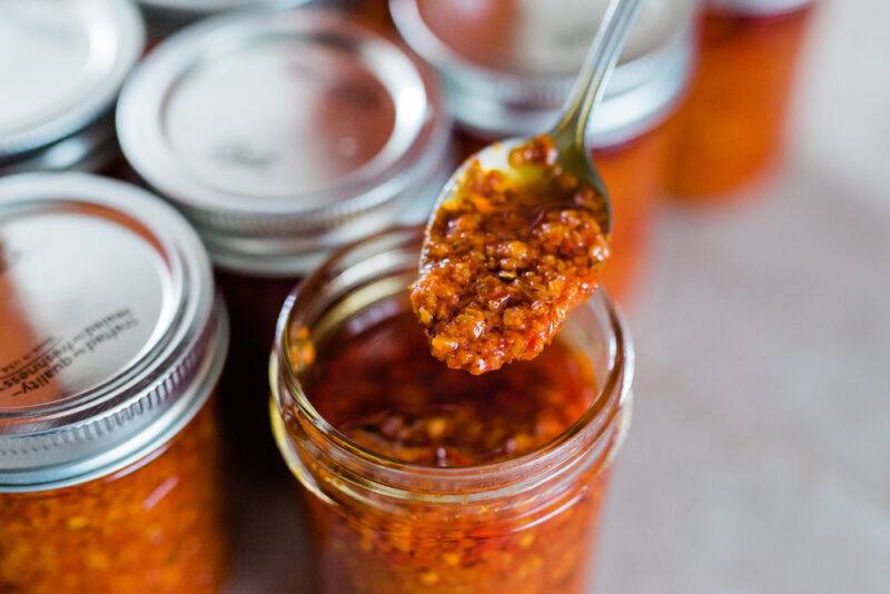 jars of chili garlic paste, one is open with a silver spoon with chili garlic paste