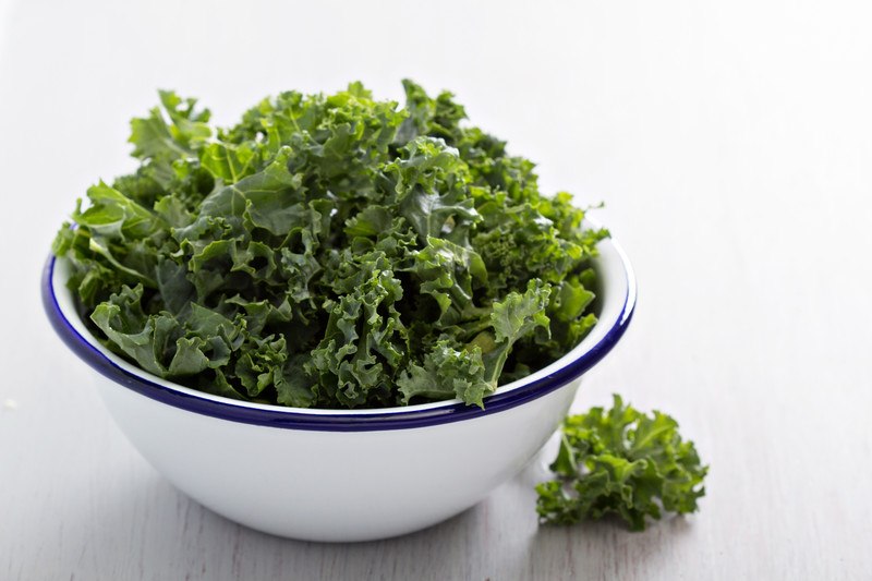 a white bowl with blue rim full of kale