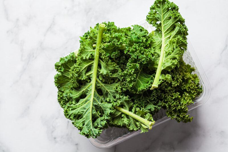 on a marbled surface is a square white dish with fresh kale