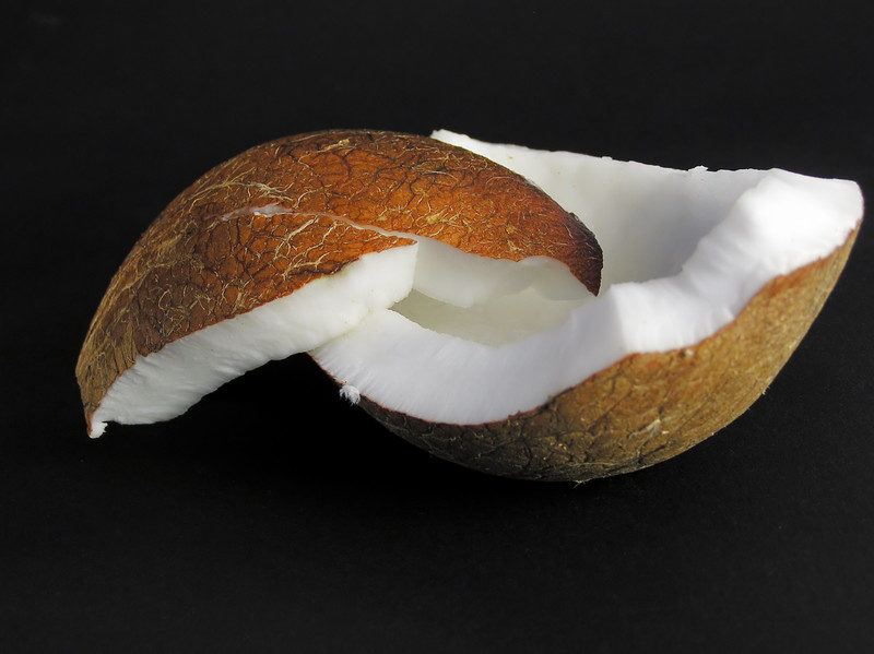 crushed coconut on black background. coconuts are popular for the keto diet.