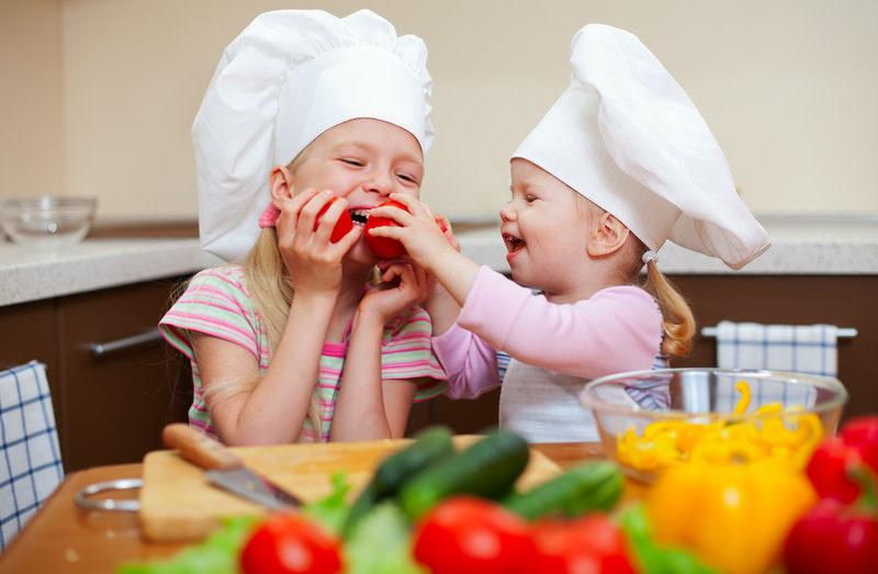 kid friendly meal kits | Food For Net two young girls in the kitchen with chef hats preparing to make a meal with peppers, cucumbers