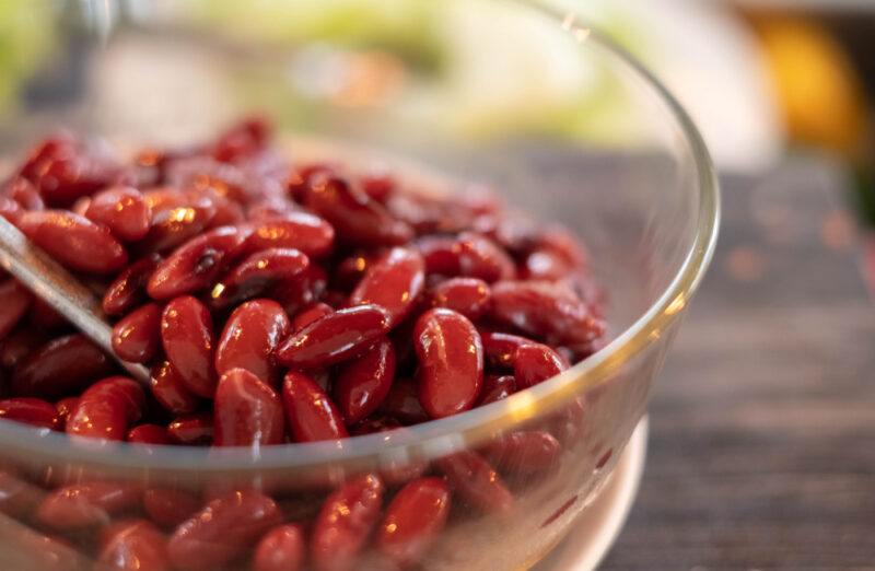 closeup shot of kidney beans in a clear glass bowl on a wooden surface