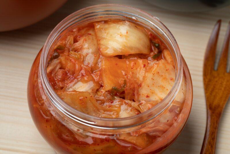 a close up image of a glass jar of kimchi