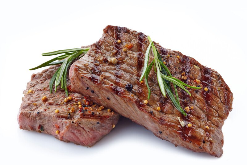 This photo shows two slices of cooked lean beef garnished with rosemary, against a white background.