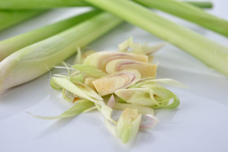 closeup image of lemongrass stalks on a white surface with some of it sliced thinly