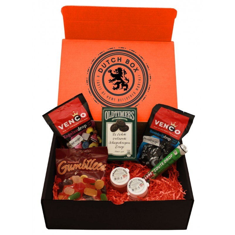 Open box with Dutch Box logo on the inside of the lid and orange raffia on the bottom with 7 different dutch licorice varieties